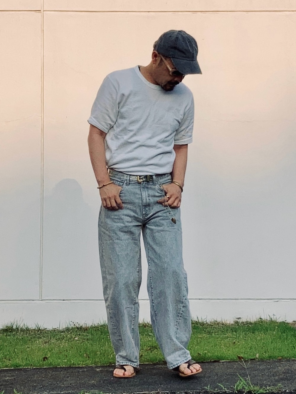 グレー系のデニムパンツ、ホワイト系のTシャツ/カットソー、ブラウン系のサンダルを着用したメンズの夏コーディネートの3枚目の写真