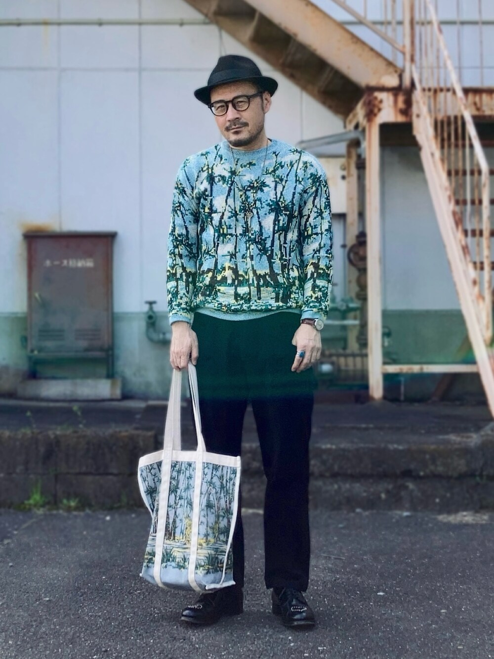 ブラック系のパンツ、ブルー系のニット/セーター、ブラック系のドレスシューズを着用したメンズの春コーディネートの3枚目の写真