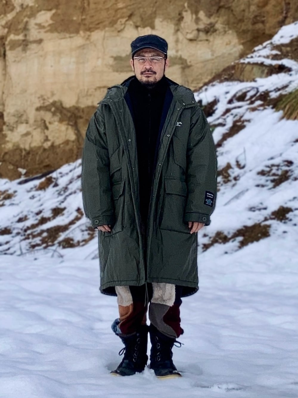 グリーン系のミリタリージャケット、ブラック系のその他アウター、その他のスウェットパンツを着用したメンズの冬コーディネートの2枚目の写真