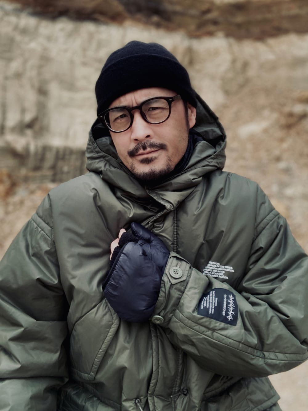 ブルー系のTシャツ/カットソー、ブラック系のベスト、グリーン系のミリタリージャケットを着用したメンズの冬コーディネートの5枚目の写真