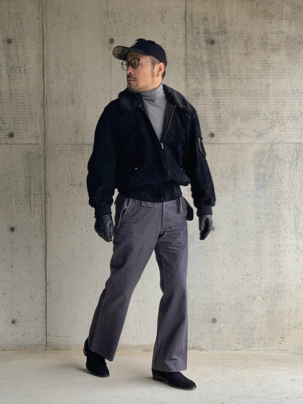 グレー系のニット/セーター、ブラック系のブルゾン、グレー系のスラックスを着用したメンズの冬コーディネートの2枚目の写真