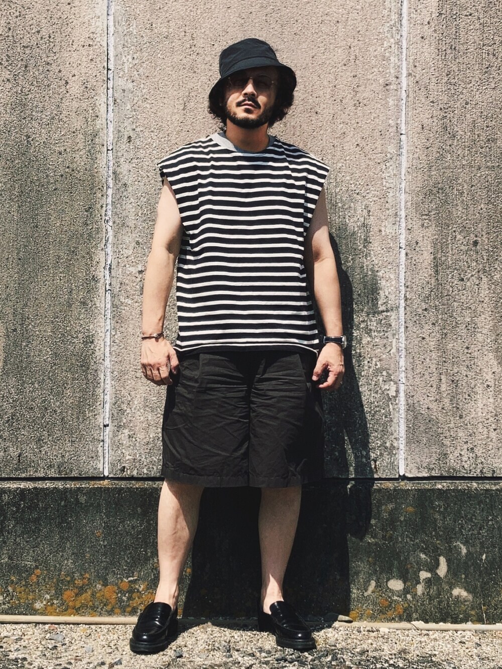 ブラック系のTシャツ/カットソー、ブラック系のローファー、ブラウン系のパンツを着用したメンズの夏コーディネートの2枚目の写真