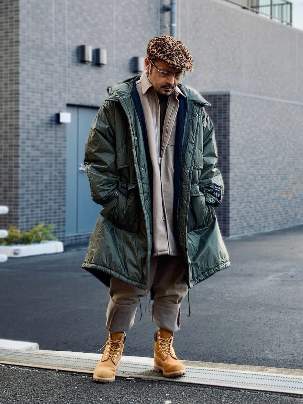 ベージュ系のシャツ/ブラウス、ベージュ系のスウェットパンツ、グリーン系のミリタリージャケットを着用したメンズの冬コーディネートの2枚目の写真