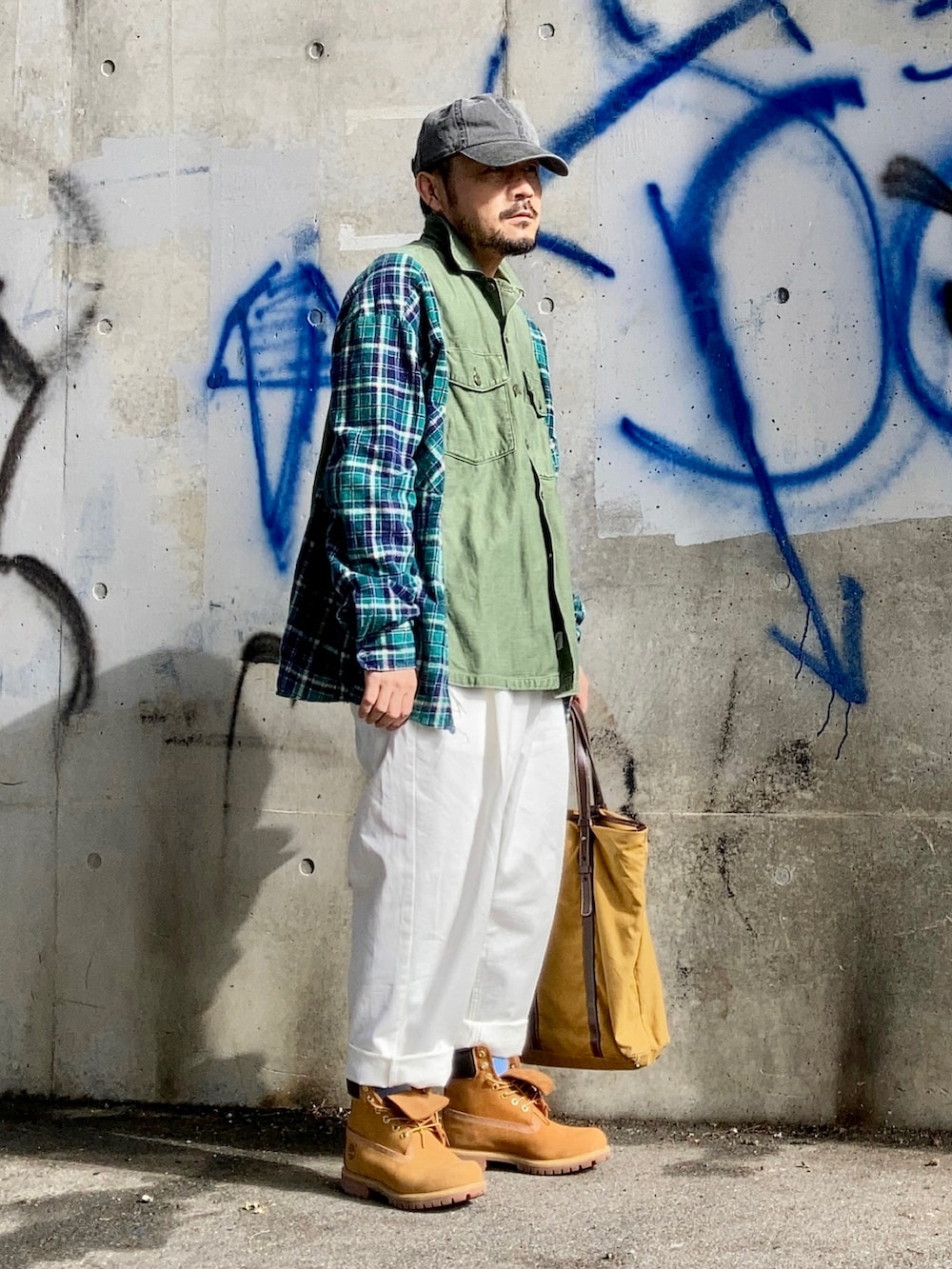 グリーン系のシャツ/ブラウス、ホワイト系のスラックス、イエロー系のブーツを着用したメンズの春コーディネートの2枚目の写真