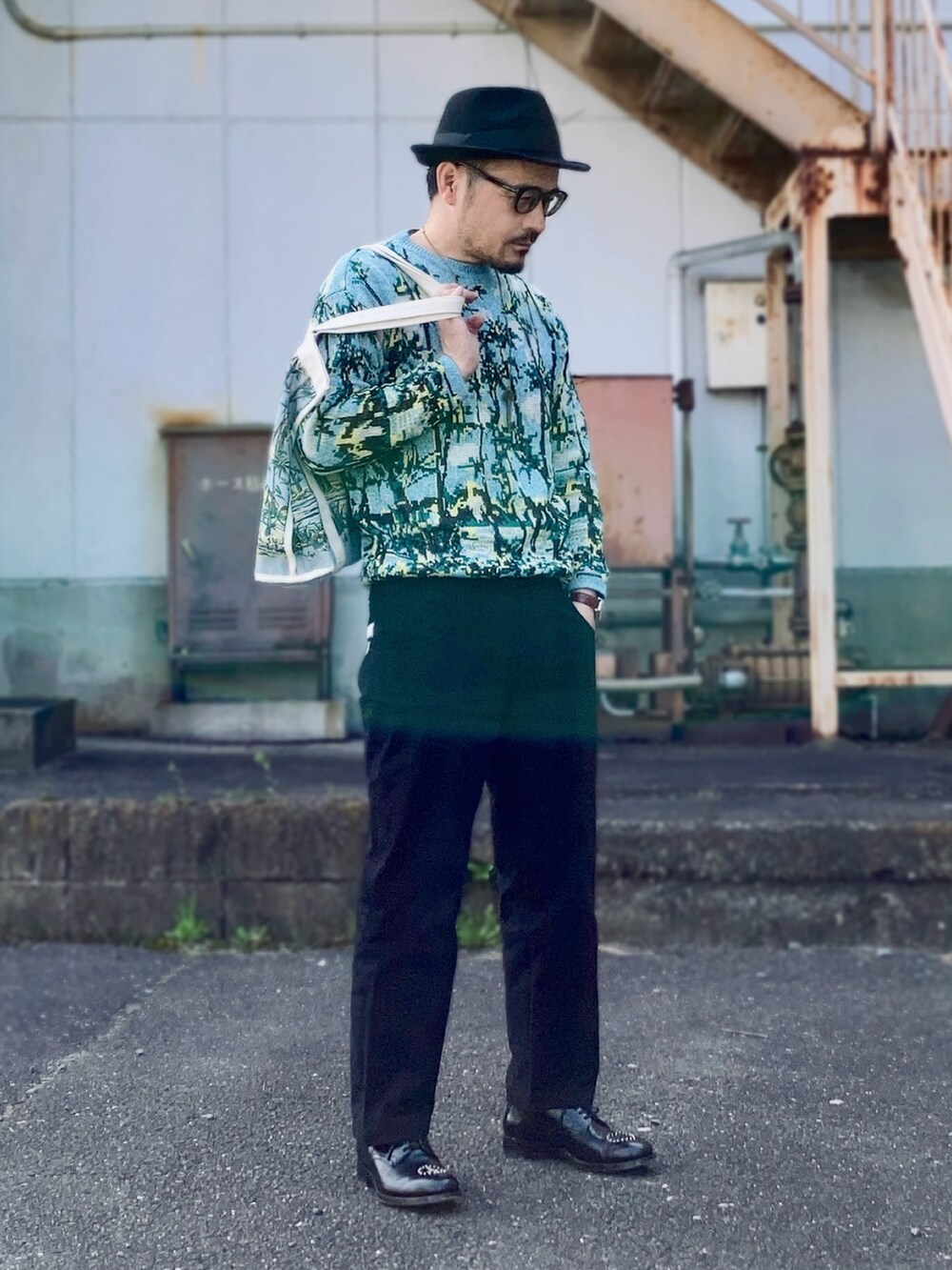 ブラック系のパンツ、ブルー系のニット/セーター、ブラック系のドレスシューズを着用したメンズの春コーディネートの2枚目の写真