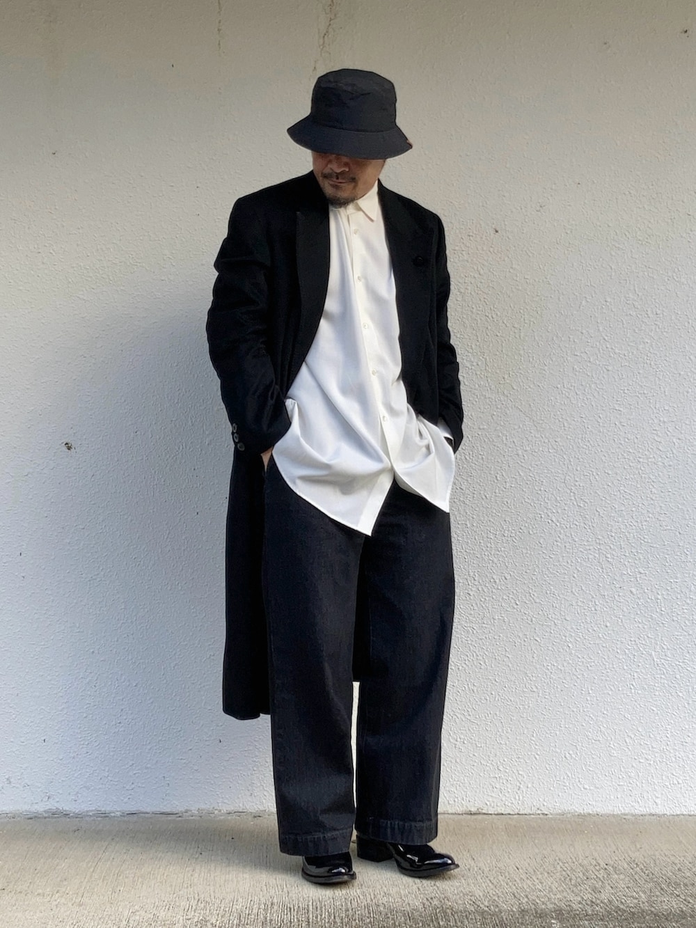 ホワイト系のシャツ/ブラウス、ブラック系のチェスターコート、ブラック系のデニムパンツを着用したメンズの冬コーディネートの3枚目の写真