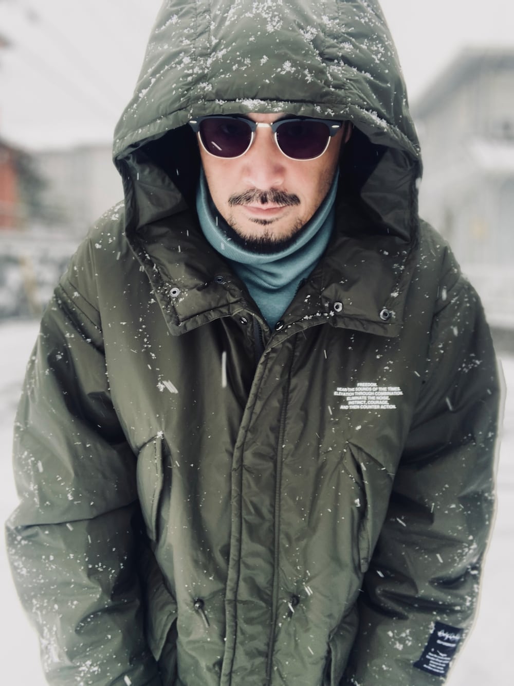 ブルー系のニット/セーター、グリーン系のミリタリージャケット、ブラック系のその他パンツを着用したメンズの冬コーディネートの4枚目の写真