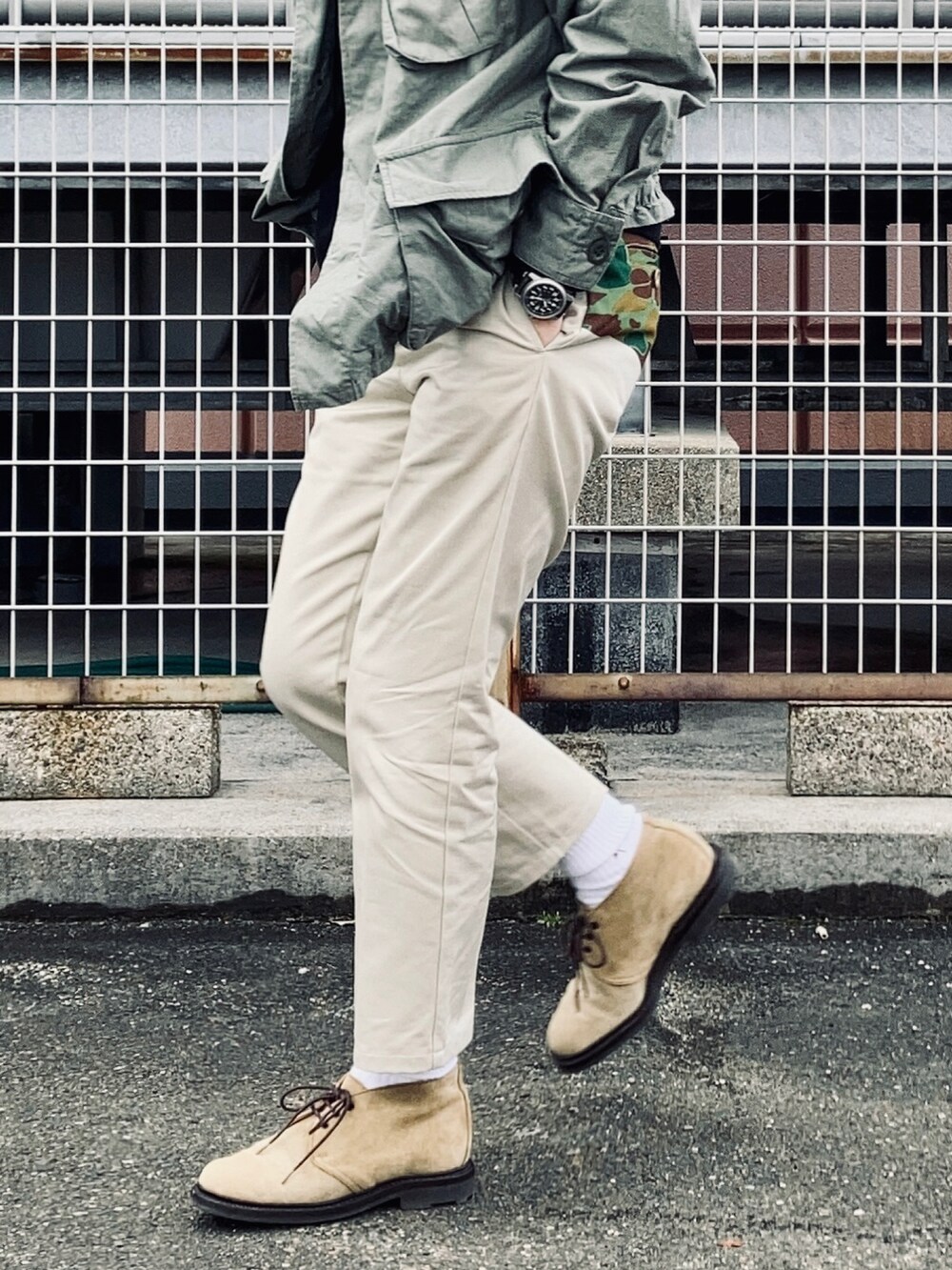 ブラック系のパーカー、グリーン系のミリタリージャケット、ベージュ系のチノパンツを着用したメンズの冬コーディネートの2枚目の写真