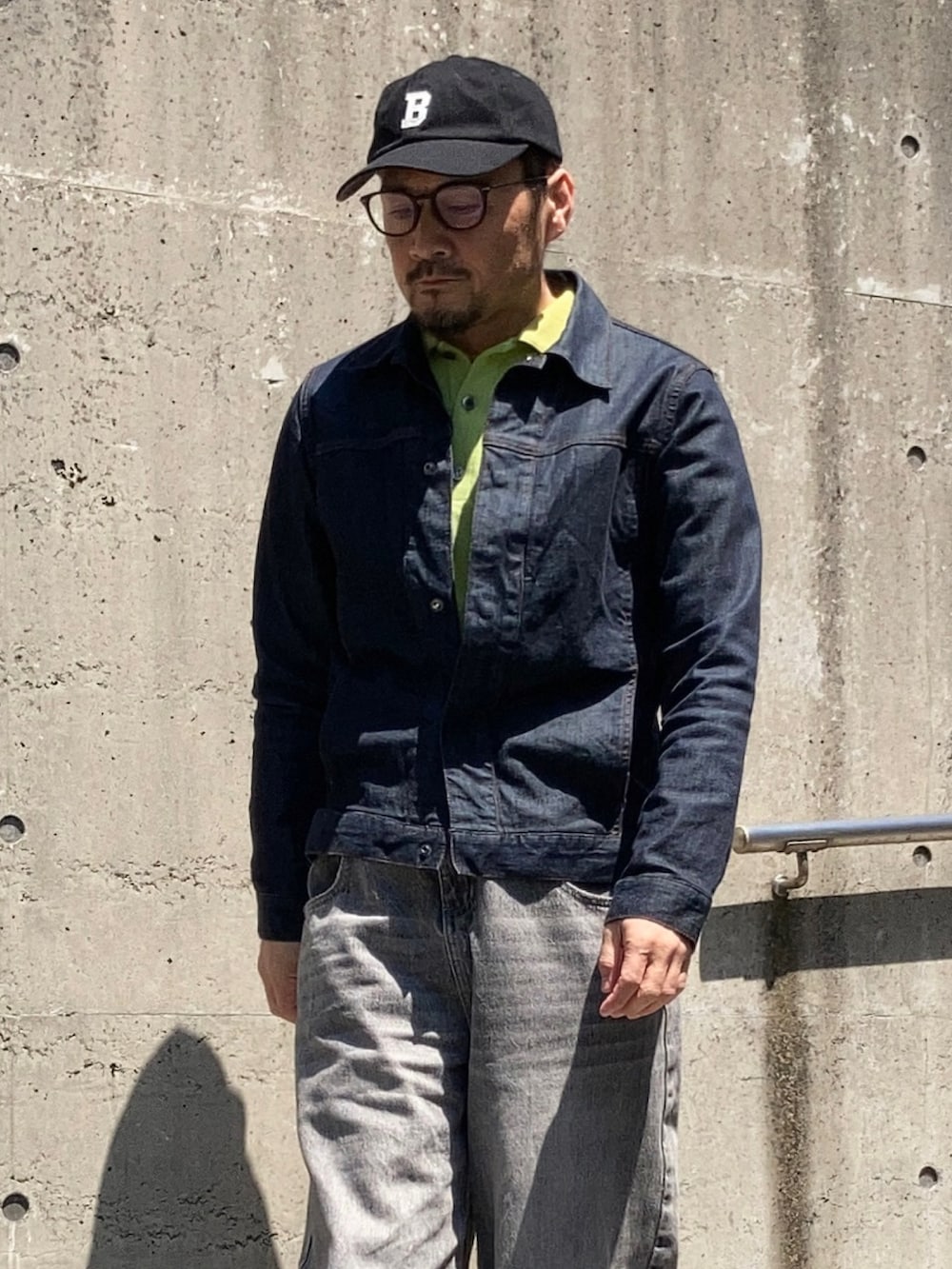 グリーン系のポロシャツ、ブルー系のデニムジャケット、グレー系のデニムパンツを着用したメンズの春コーディネートの3枚目の写真