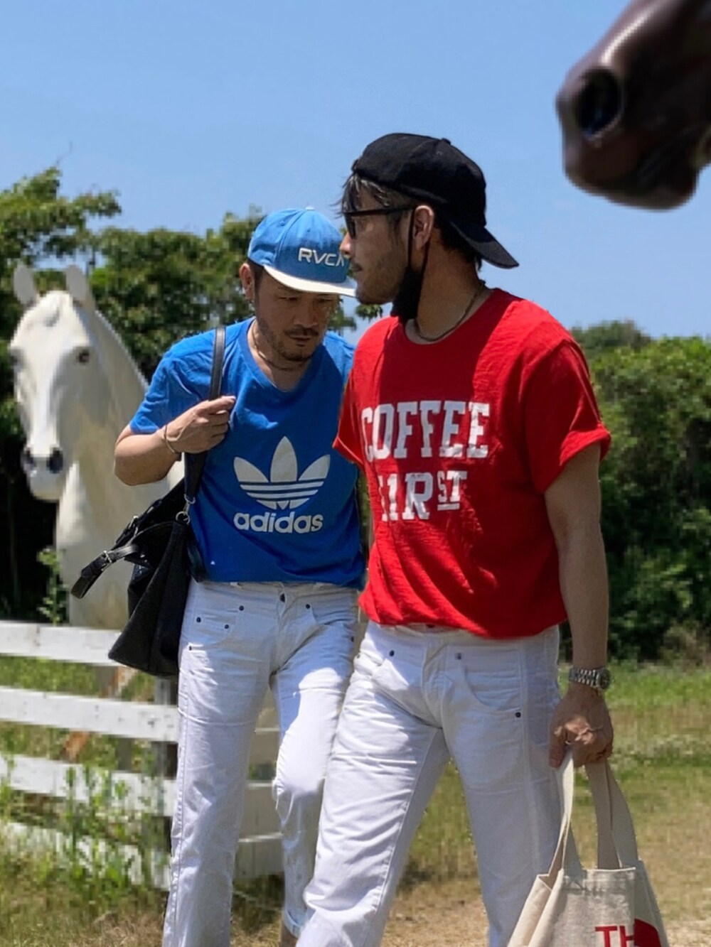 レッド系のTシャツ/カットソー、ブルー系のTシャツ/カットソー、ホワイト系のデニムパンツを着用したメンズの春コーディネートの4枚目の写真