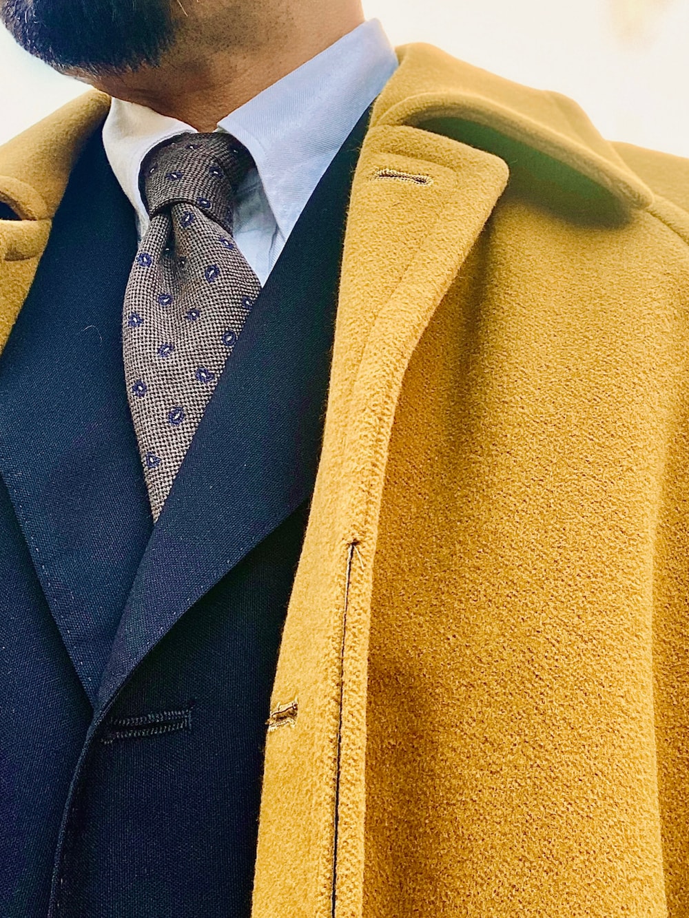 イエロー系のステンカラーコート、グリーン系のその他パンツ、ブラウン系のドレスシューズを着用したメンズの冬コーディネートの2枚目の写真