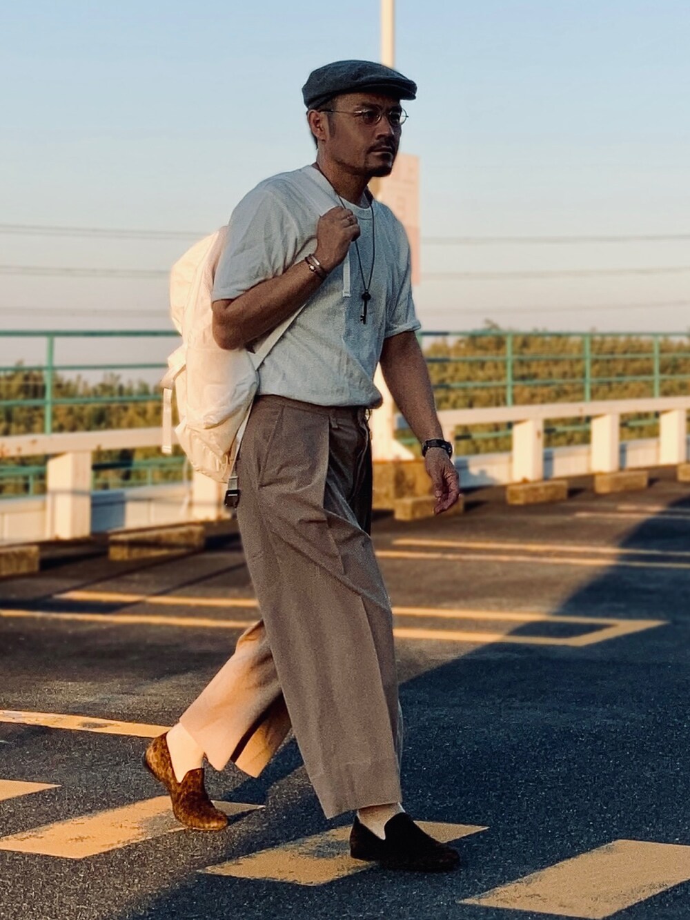 ホワイト系のTシャツ/カットソー、ベージュ系のスラックス、ブラウン系のスリッポンを着用したメンズの秋コーディネートの2枚目の写真