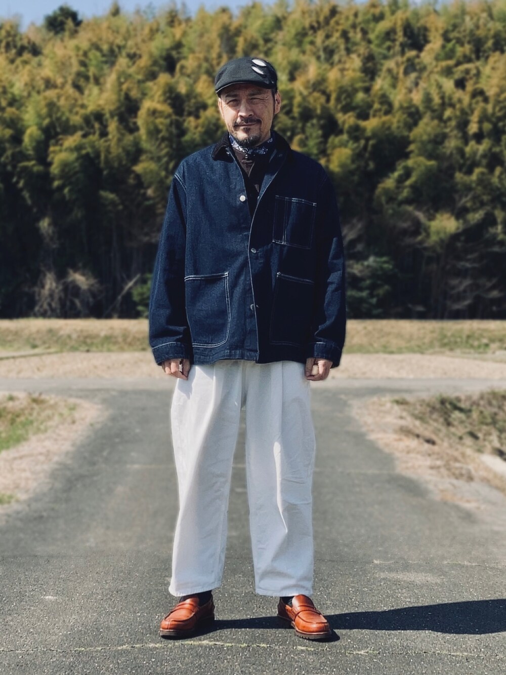 ブラウン系のTシャツ/カットソー、ブルー系のデニムジャケット、ホワイト系のスラックスを着用したメンズの春コーディネートの2枚目の写真