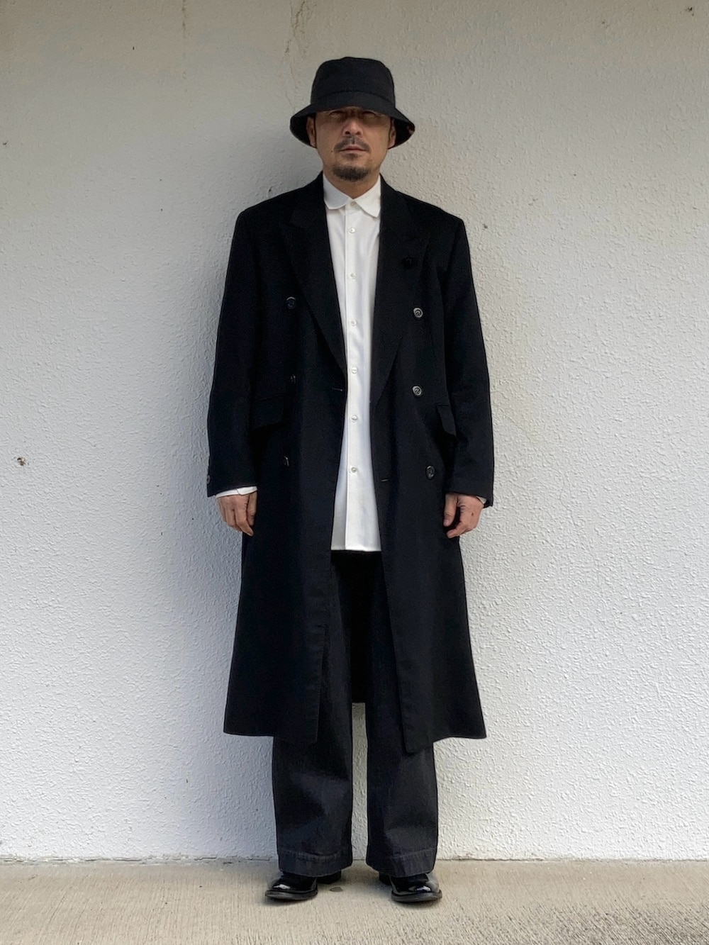 ホワイト系のシャツ/ブラウス、ブラック系のチェスターコート、ブラック系のデニムパンツを着用したメンズの冬コーディネートの2枚目の写真