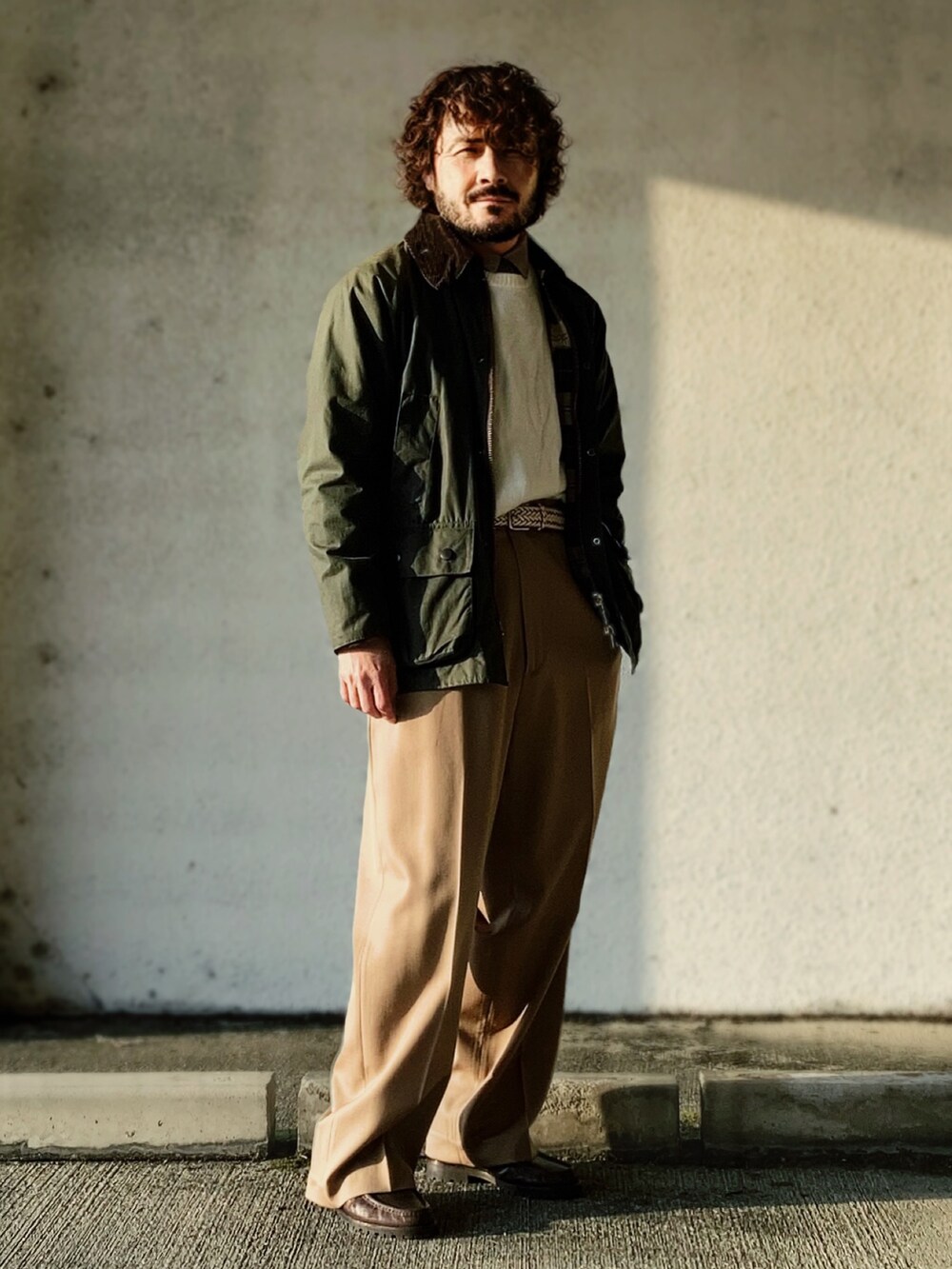 グリーン系のその他アウター、その他のニット/セーター、ベージュ系のスラックスを着用したメンズの冬コーディネートの2枚目の写真