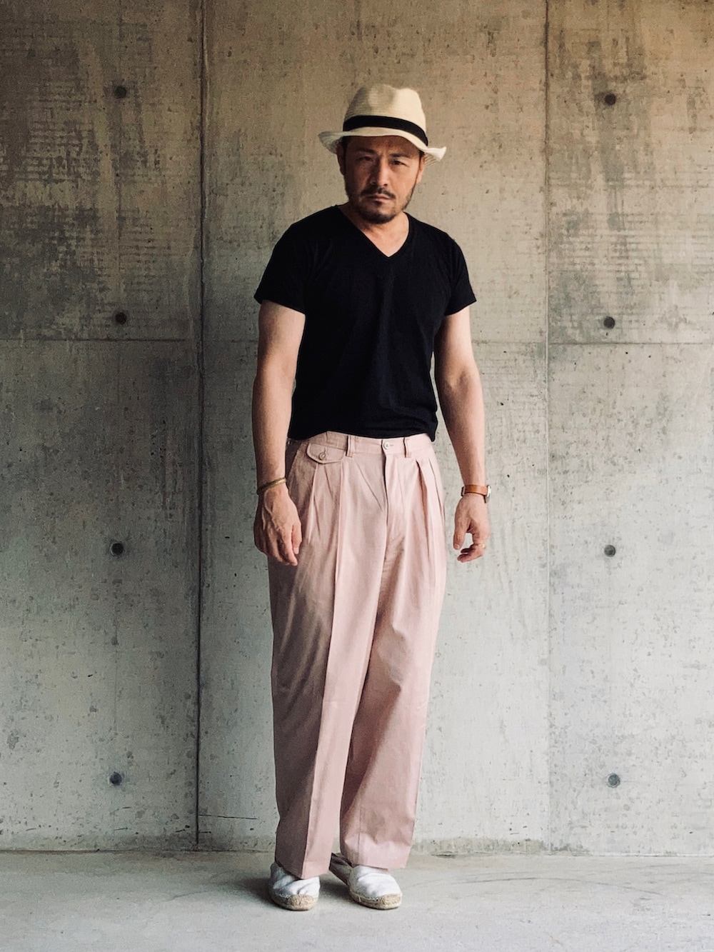 ブラック系のTシャツ/カットソー、ピンク系のスラックス、ホワイト系のスリッポンを着用したメンズの夏コーディネートの3枚目の写真