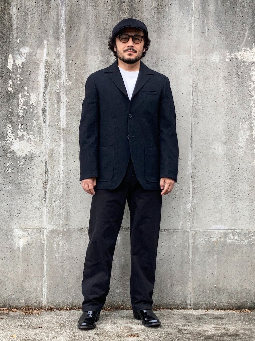 ホワイト系のTシャツ/カットソー、ブラック系のテーラードジャケット、ブラック系のパンツを着用したメンズの秋コーディネートの3枚目の写真