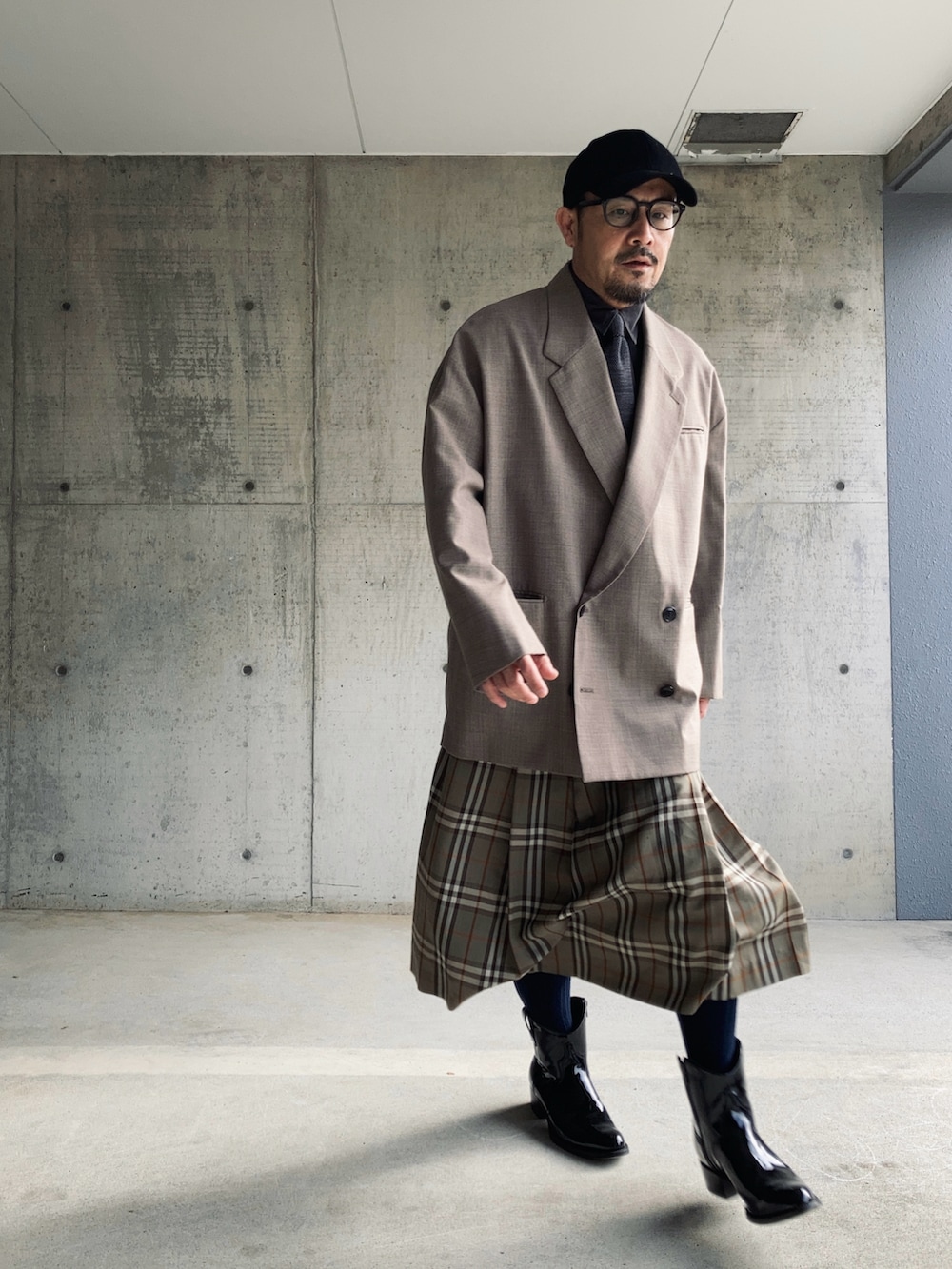 グレー系のスカート、ブラウン系のテーラードジャケット、ブラック系のブーツを着用したメンズの冬コーディネートの2枚目の写真