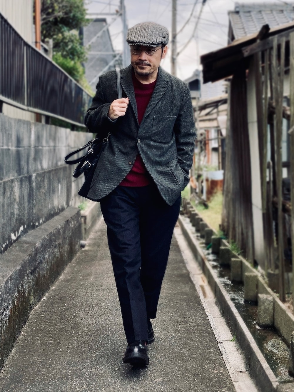 レッド系のニット/セーター、グレー系のテーラードジャケット、ブラック系のスラックスを着用したメンズの秋コーディネートの2枚目の写真