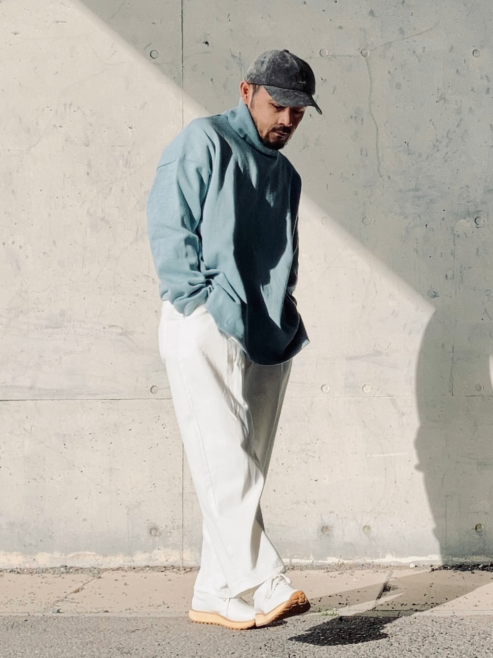 ブルー系のニット/セーター、ホワイト系のスラックス、ホワイト系のスニーカーを着用したメンズの春コーディネートの3枚目の写真