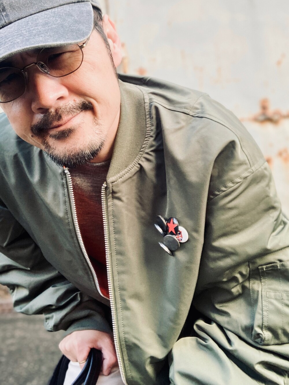 グレー系のニット/セーター、グリーン系のMA-1、ベージュ系のチノパンツを着用したメンズの秋コーディネートの5枚目の写真