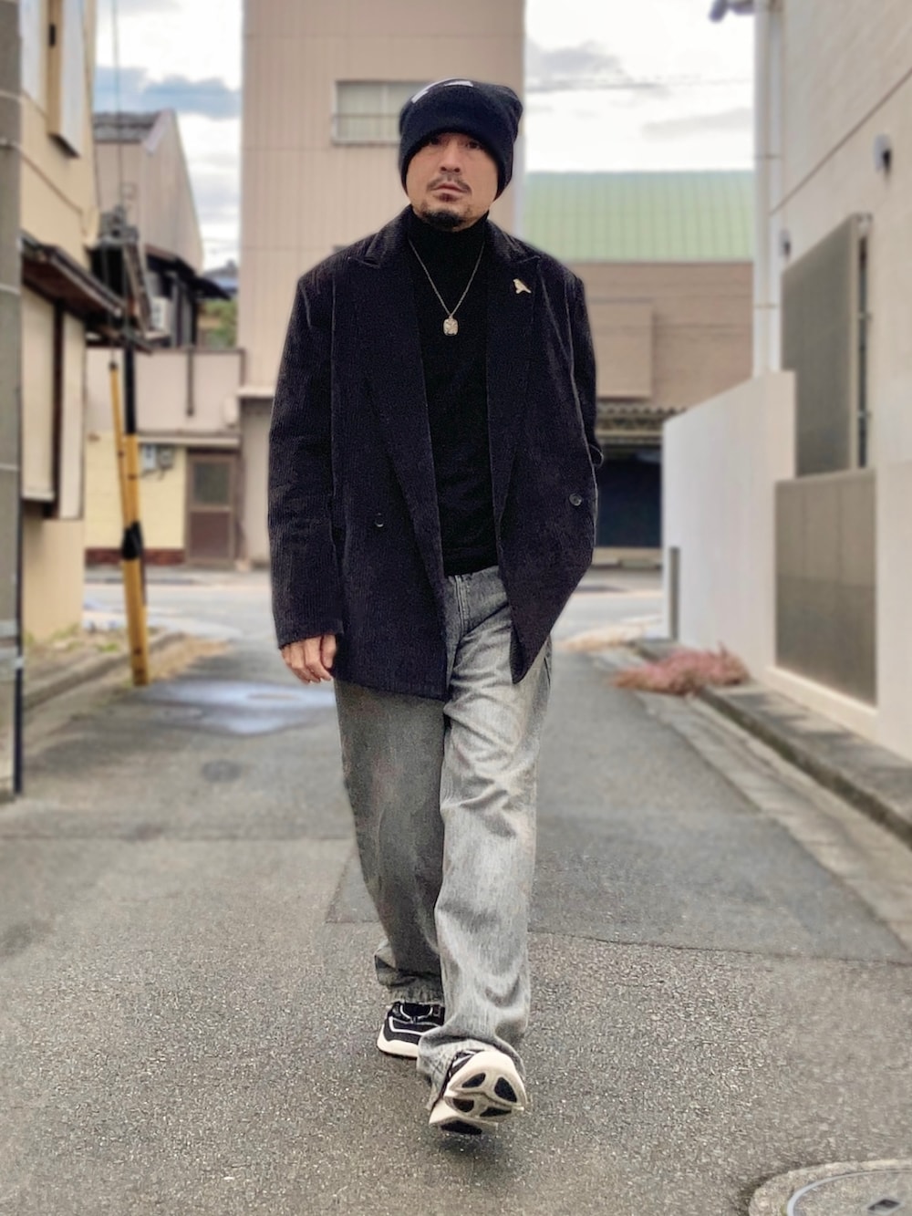 ブラック系のニット/セーター、グレー系のテーラードジャケット、グレー系のデニムパンツを着用したメンズの冬コーディネートの2枚目の写真