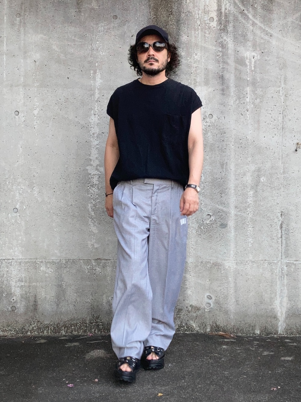 グレー系のスラックス、ブラック系のその他トップス、ブラック系のサンダルを着用したメンズの夏コーディネートの4枚目の写真
