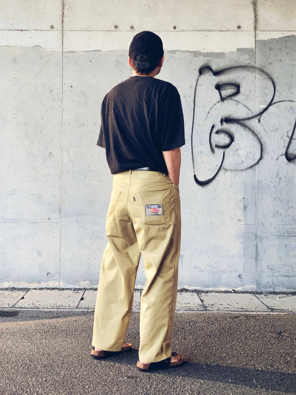 グレー系のTシャツ/カットソー、ベージュ系のチノパンツ、ブラック系のサンダルを着用したメンズの夏コーディネートの3枚目の写真