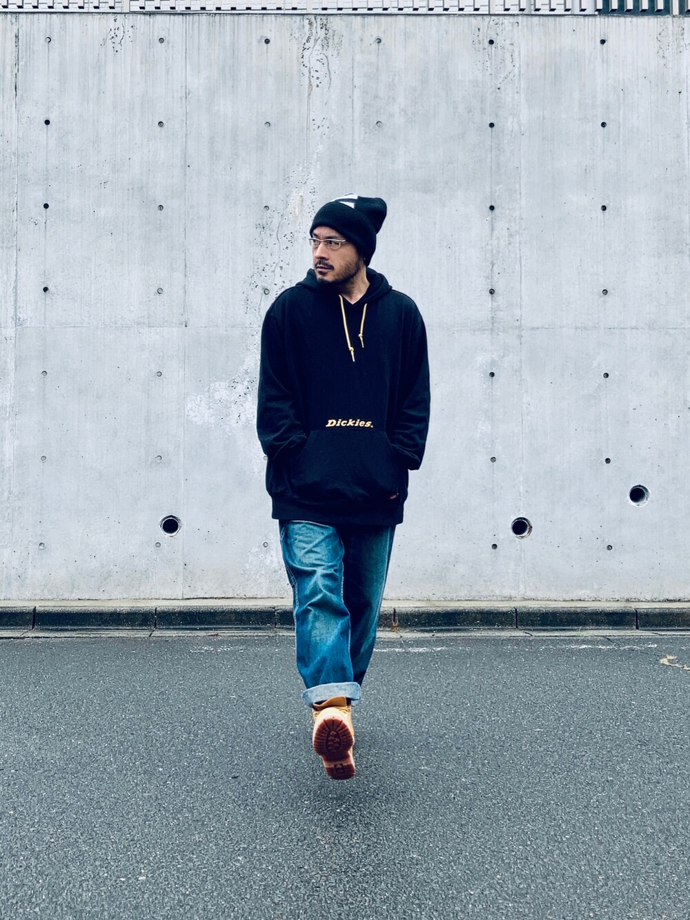 ブラック系のパーカー、ブルー系のデニムパンツ、イエロー系のブーツを着用したメンズの秋コーディネートの3枚目の写真