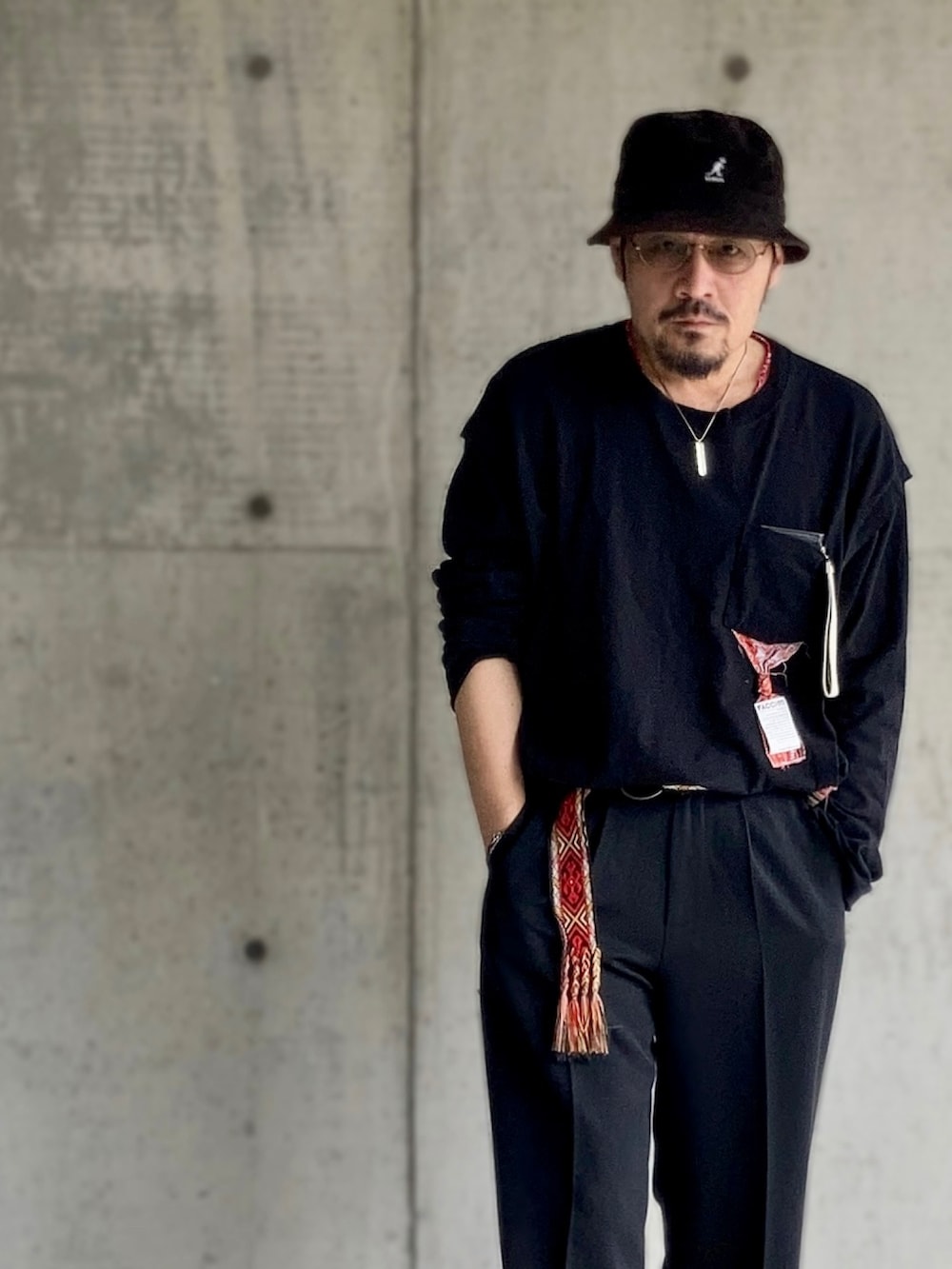 ブラック系のTシャツ/カットソー、ブラック系のスラックス、レッド系のスニーカーを着用したメンズの春コーディネートの4枚目の写真