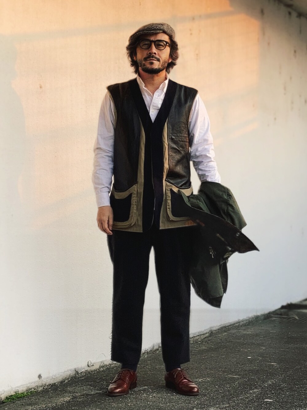 グリーン系のその他アウター、ブラック系のスラックス、ブラウン系のドレスシューズを着用したメンズの春コーディネートの3枚目の写真