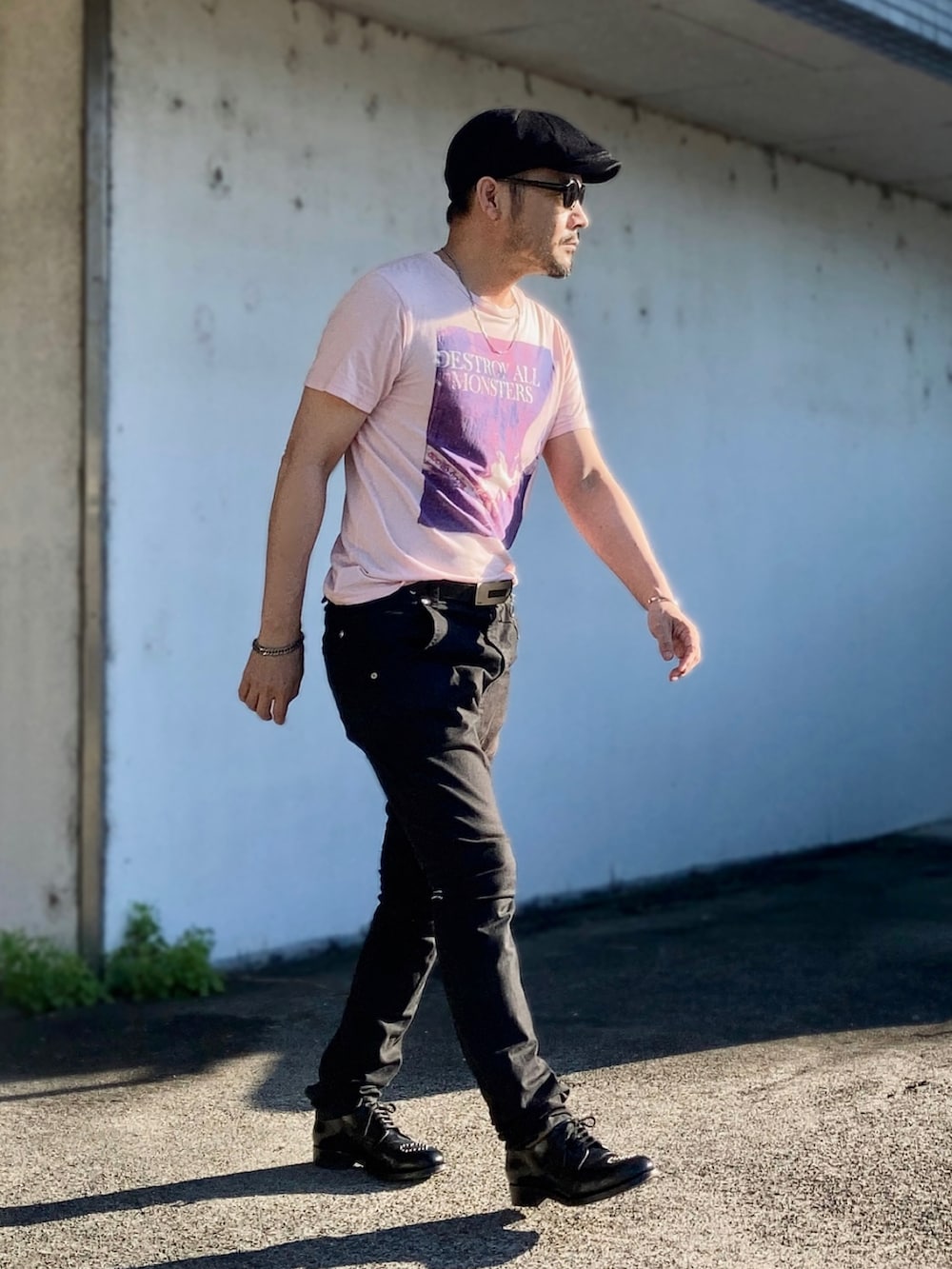ピンク系のTシャツ/カットソー、ブラック系のデニムパンツ、ブラック系のドレスシューズを着用したメンズの夏コーディネートの2枚目の写真