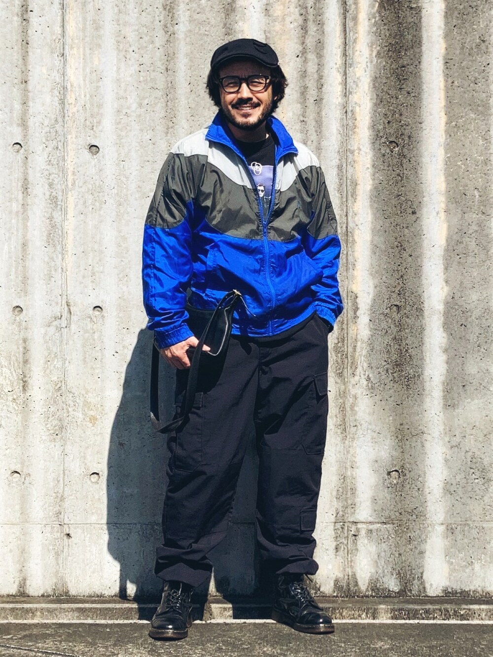 ブラック系のスウェット、ブルー系のナイロンジャケット、ブラック系のカーゴパンツを着用したメンズの春コーディネートの3枚目の写真