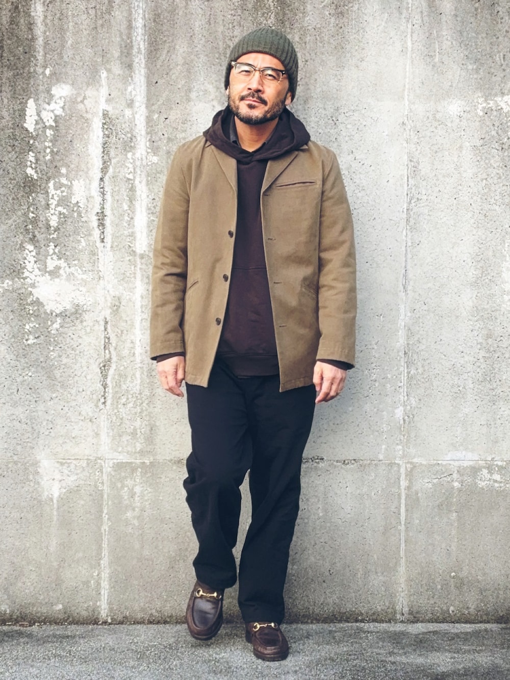 ベージュ系のテーラードジャケット、ブラウン系のパーカー、ブラック系のパンツを着用したメンズの冬コーディネートの2枚目の写真