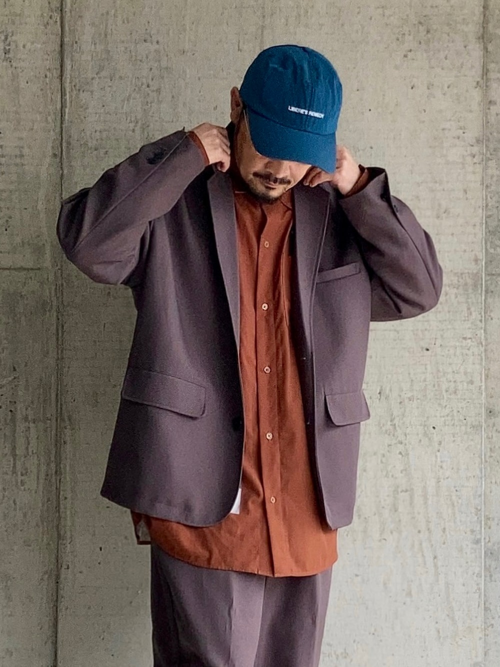 オレンジ系のシャツ/ブラウス、グレー系のセットアップ、ブラック系のスニーカーを着用したメンズの春コーディネートの3枚目の写真