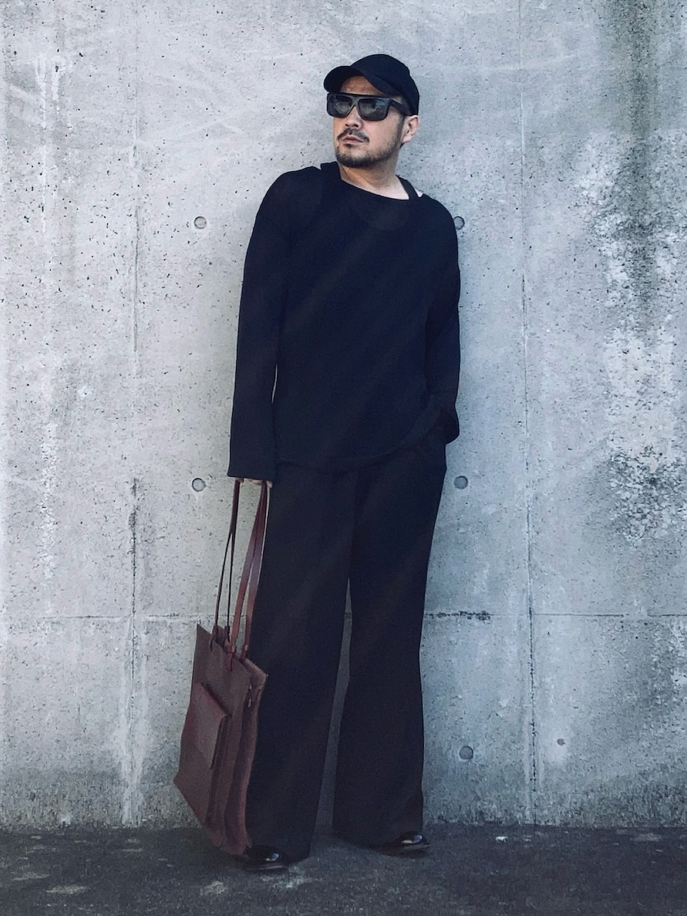 ブラック系のニット/セーター、ブラック系のスラックス、ブラック系のブーツを着用したメンズの春コーディネートの3枚目の写真