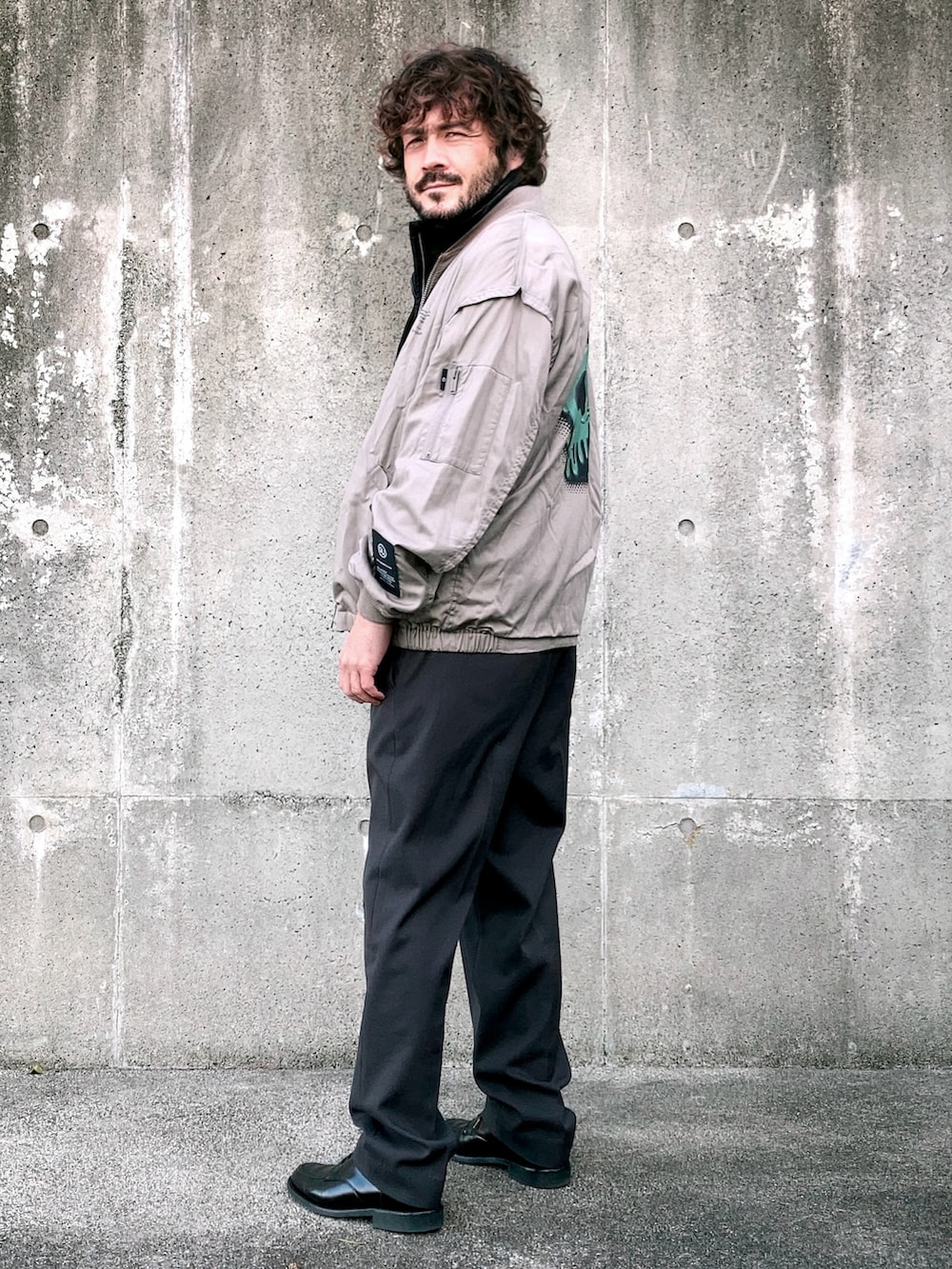 ベージュ系のMA-1、ブラック系のベスト、グレー系のスラックスを着用したメンズの冬コーディネートの2枚目の写真