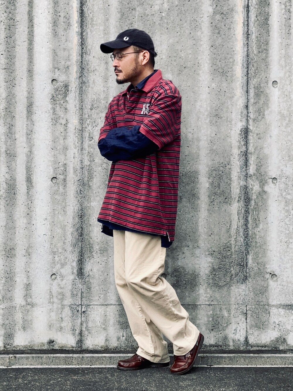 レッド系のポロシャツ、ベージュ系のチノパンツ、ブラウン系のモカシン/デッキシューズを着用したメンズの秋コーディネートの4枚目の写真