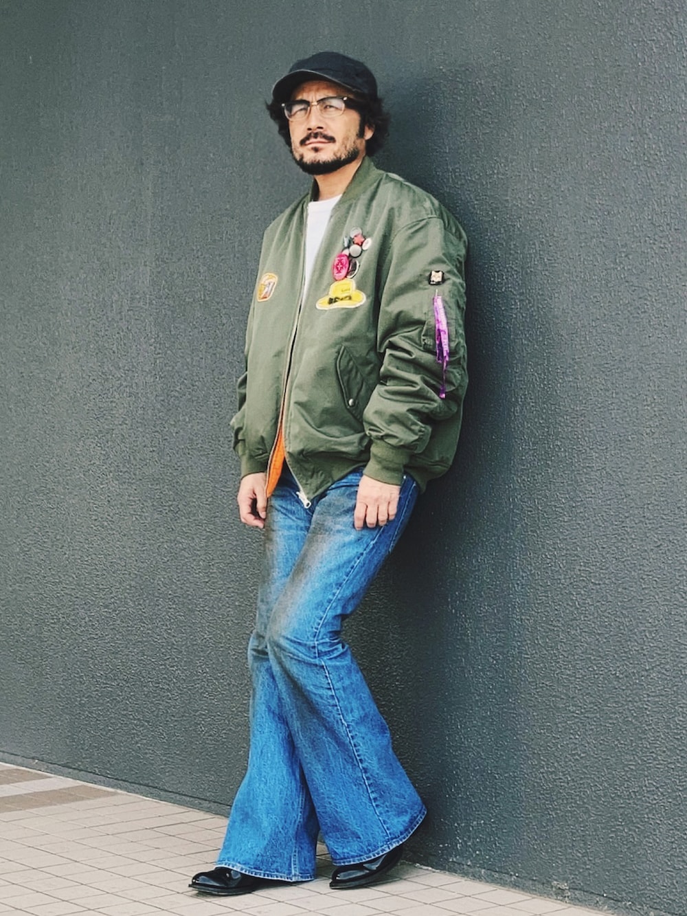 グリーン系のMA-1、ブルー系のデニムパンツ、ブラック系のブーツを着用したメンズの春コーディネートの3枚目の写真