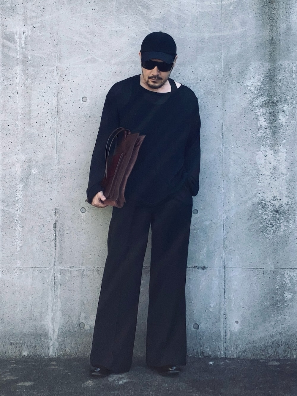 ブラック系のニット/セーター、ブラック系のスラックス、ブラック系のブーツを着用したメンズの春コーディネートの2枚目の写真