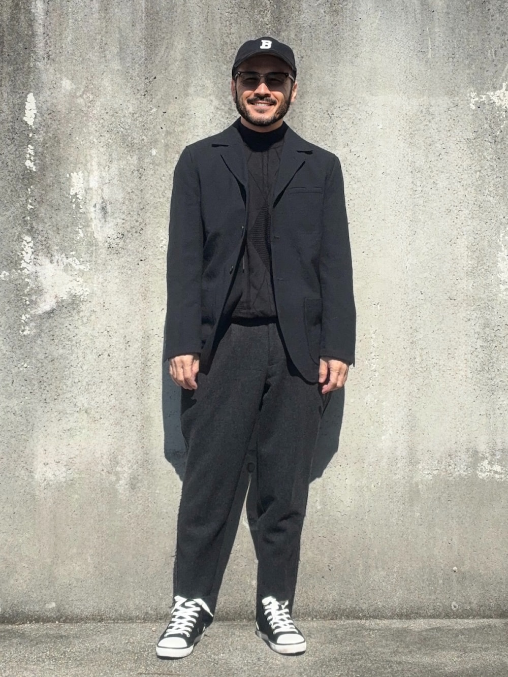 ブラック系のスニーカー、ブラック系のテーラードジャケット、ブラック系のスラックスを着用したメンズの春コーディネートの2枚目の写真