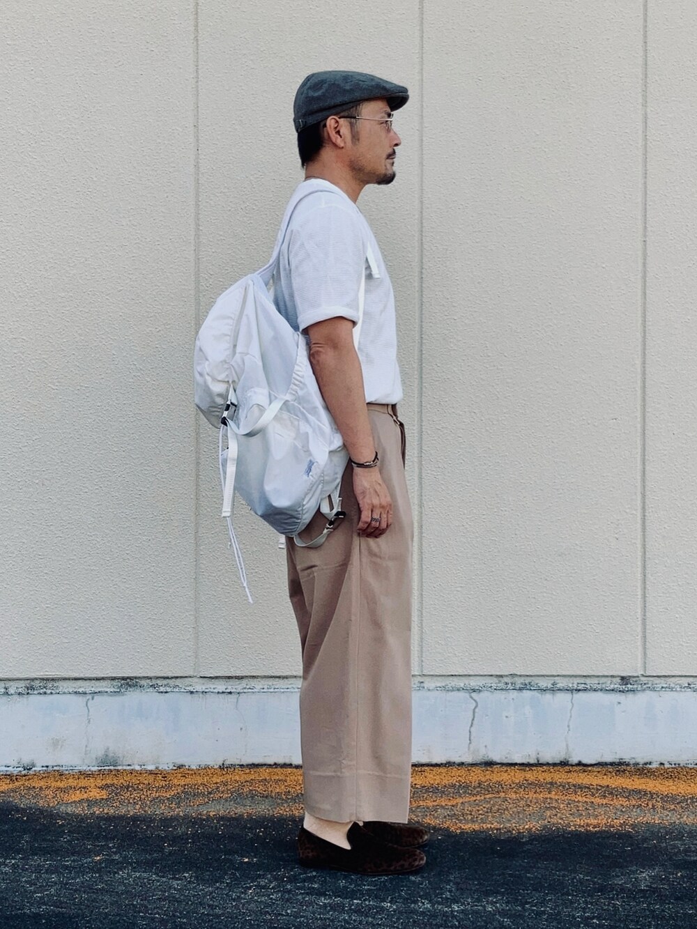 ホワイト系のTシャツ/カットソー、ベージュ系のスラックス、ブラウン系のスリッポンを着用したメンズの秋コーディネートの4枚目の写真