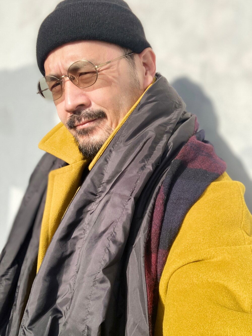 ブラック系のニット/セーター、イエロー系のステンカラーコート、ブラック系のその他パンツを着用したメンズの冬コーディネートの5枚目の写真