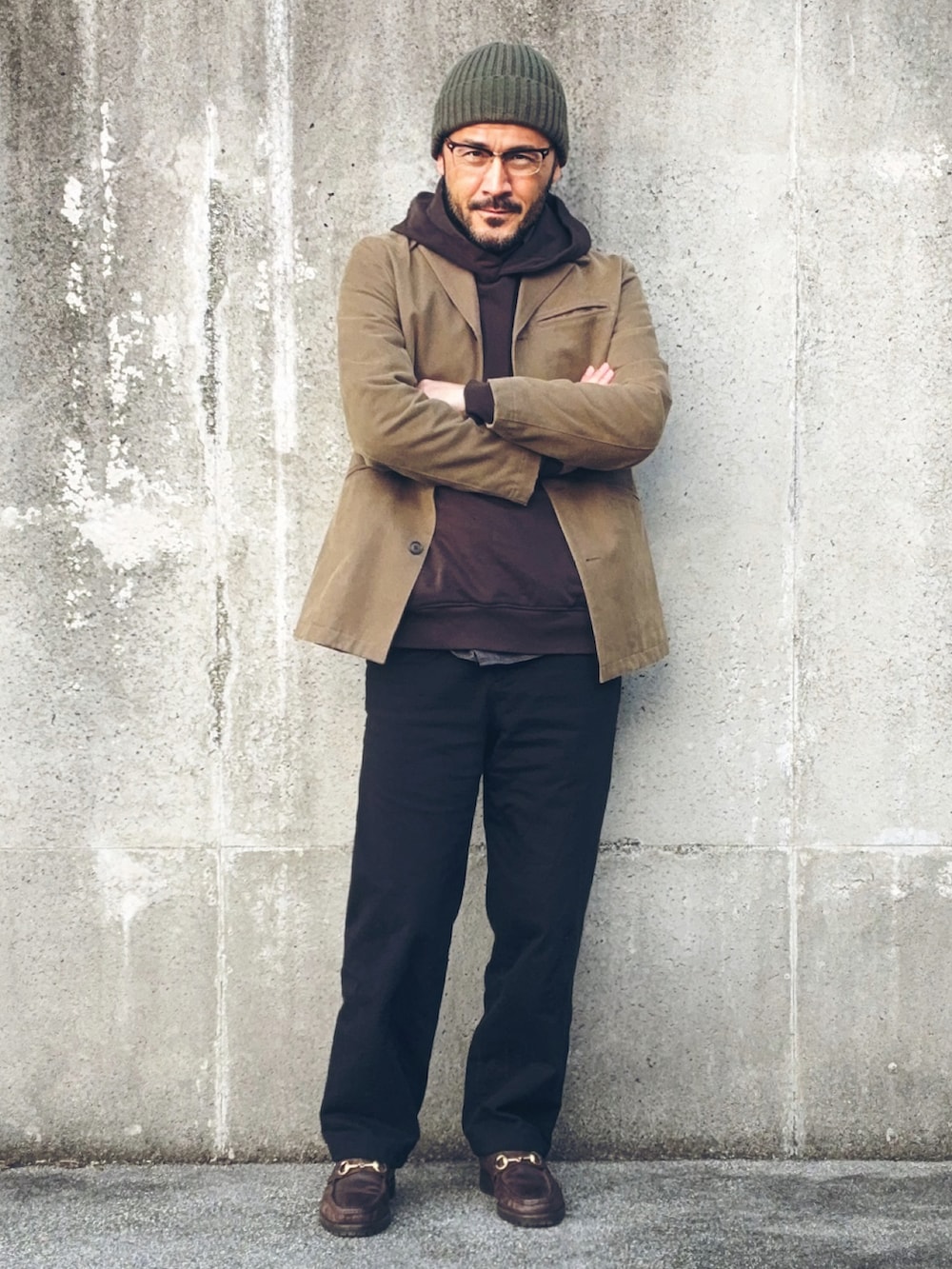 ベージュ系のテーラードジャケット、ブラウン系のパーカー、ブラック系のパンツを着用したメンズの冬コーディネートの3枚目の写真