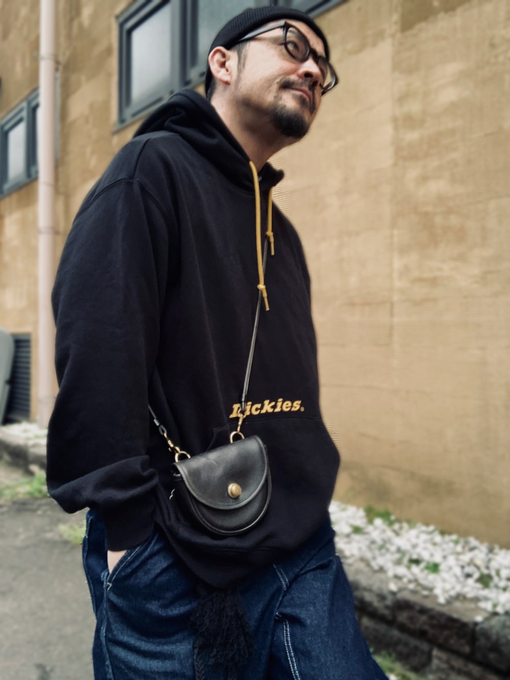 ブラック系のパーカー、ブルー系のデニムパンツ、ブラック系のスニーカーを着用したメンズの春コーディネートの4枚目の写真