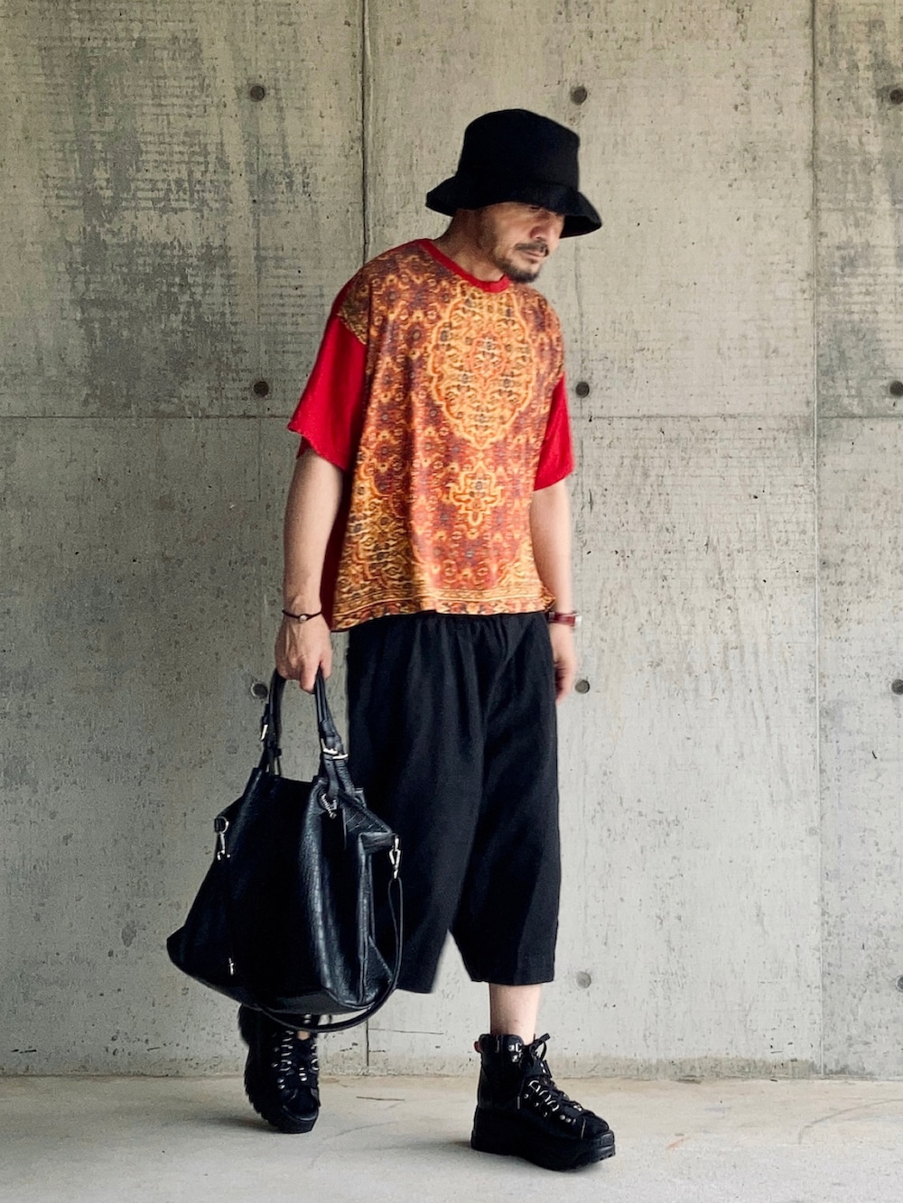 レッド系のTシャツ/カットソー、ブラック系のその他パンツ、ブラック系のサンダルを着用したメンズの夏コーディネートの2枚目の写真