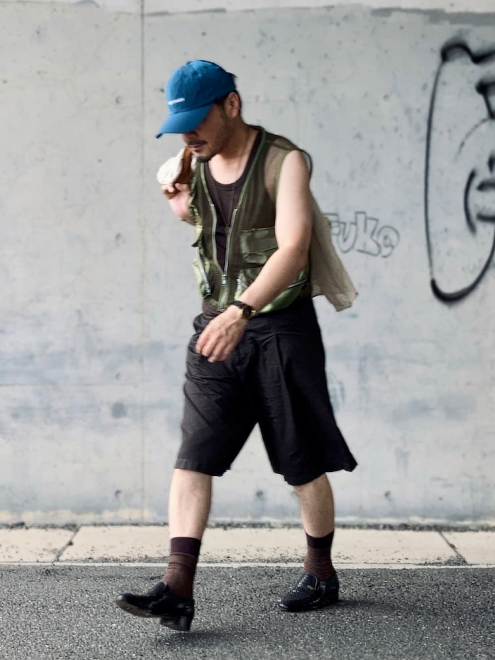 ブラウン系のタンクトップ、グリーン系のベスト、ブラウン系のパンツを着用したメンズの夏コーディネートの3枚目の写真