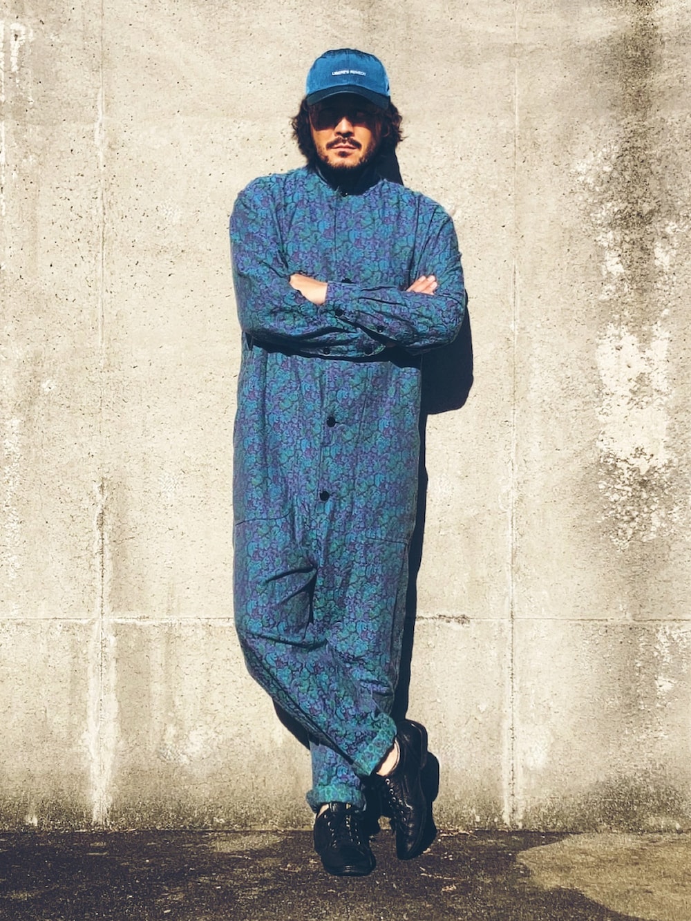 ブルー系のつなぎ/オールインワン、ブラック系のスニーカー、ブルー系のキャップを着用したメンズの秋コーディネートの2枚目の写真