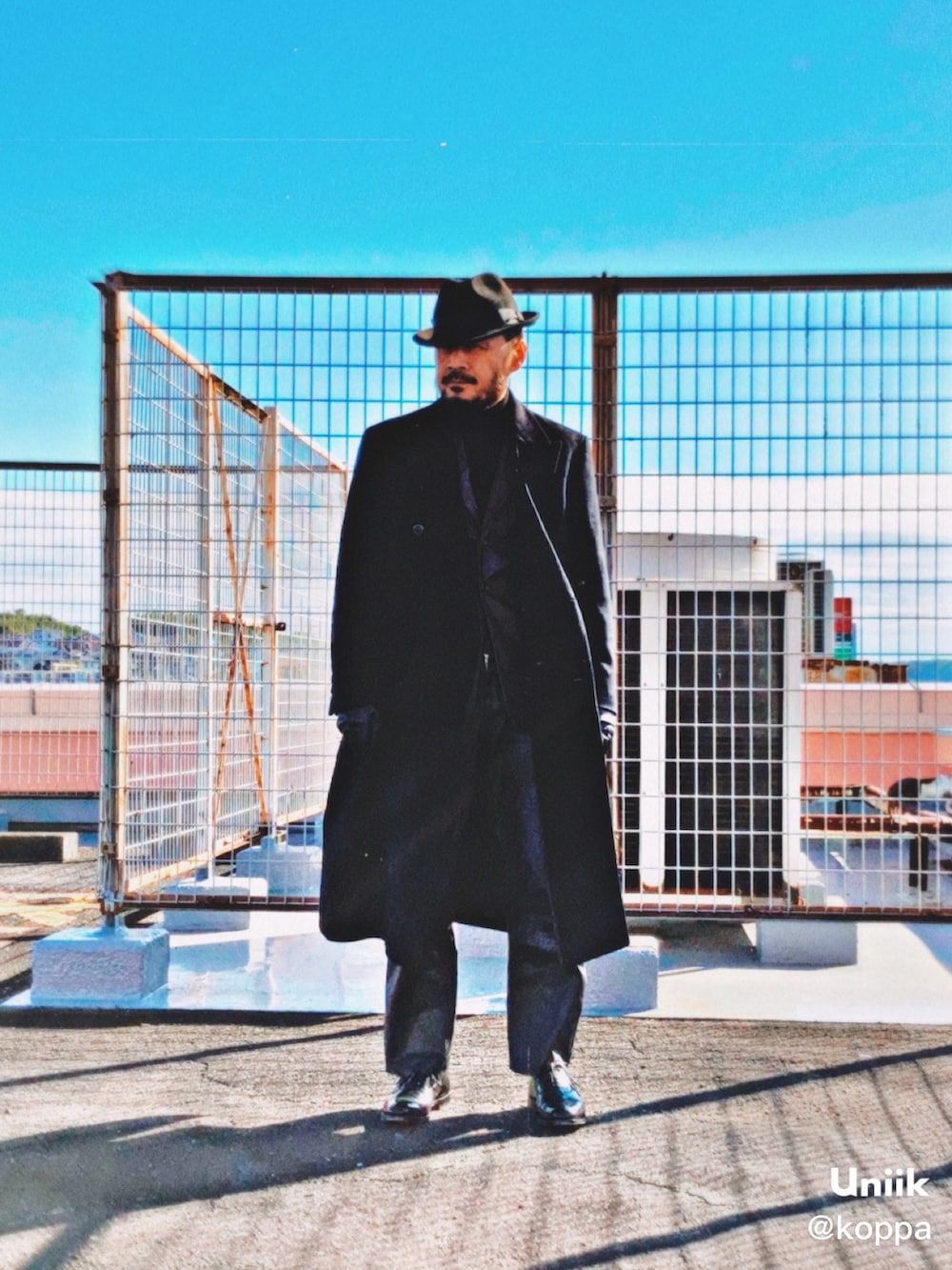 ブラウン系のテーラードジャケット、ブラック系のチェスターコート、ブラック系のニット/セーターを着用したメンズの冬コーディネートの2枚目の写真