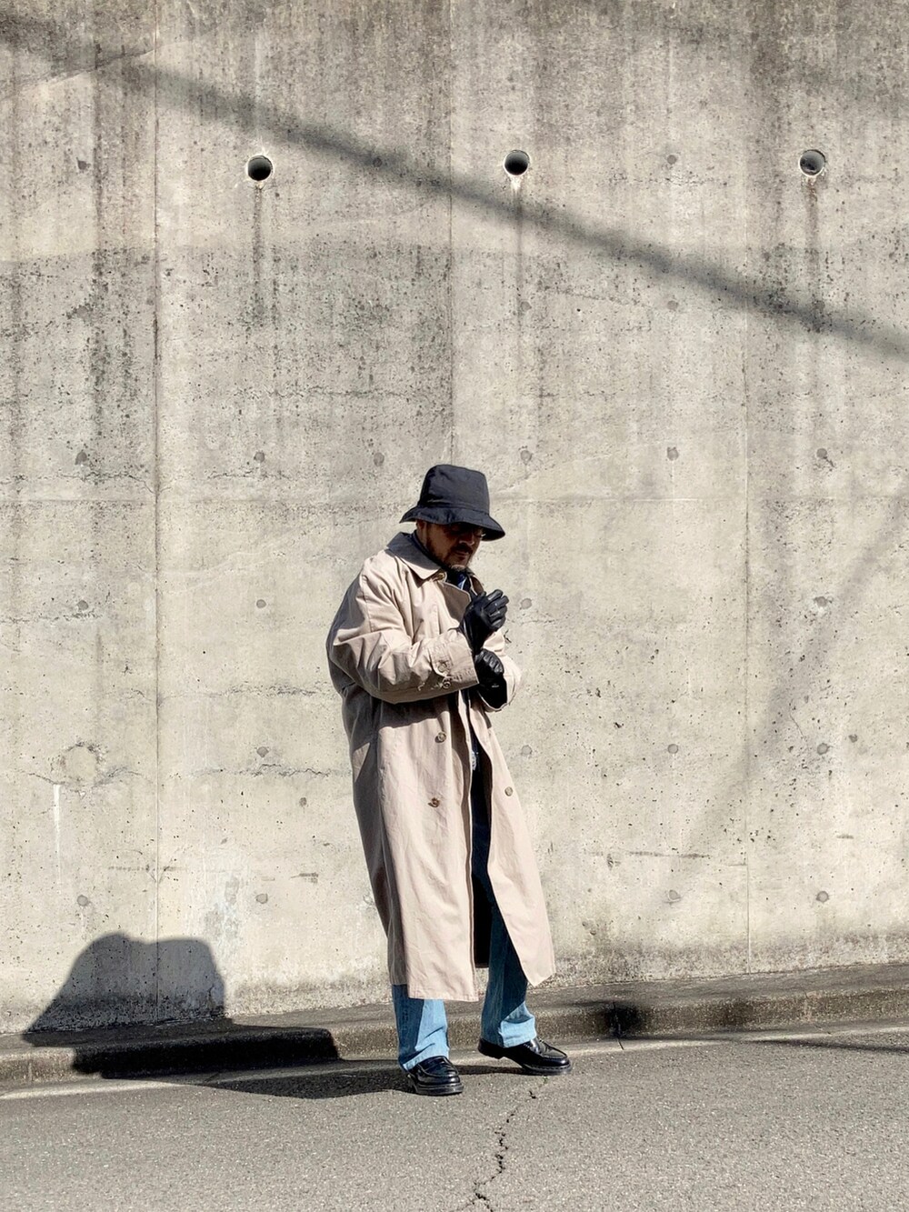 グレー系のニット/セーター、ブルー系のデニムジャケット、ベージュ系のトレンチコートを着用したメンズの冬コーディネートの3枚目の写真